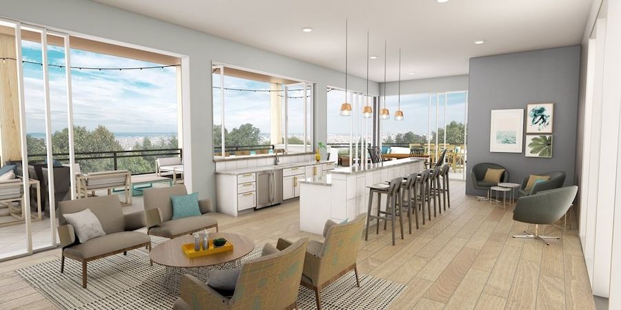 Community gathering space with tables, chairs, and a counter overlooking a balcony view.