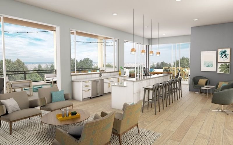 <span class="uk-h4">Community gathering space with tables, chairs, and a counter overlooking a balcony view.</span>